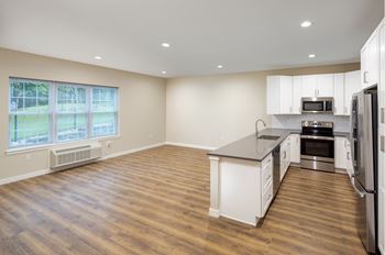An empty kitchen with an island and stainless steel appliances